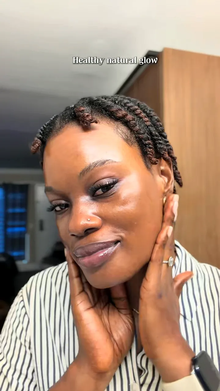 Creator with twisted hair in a striped shirt framing her face with both hands to show glowing skin