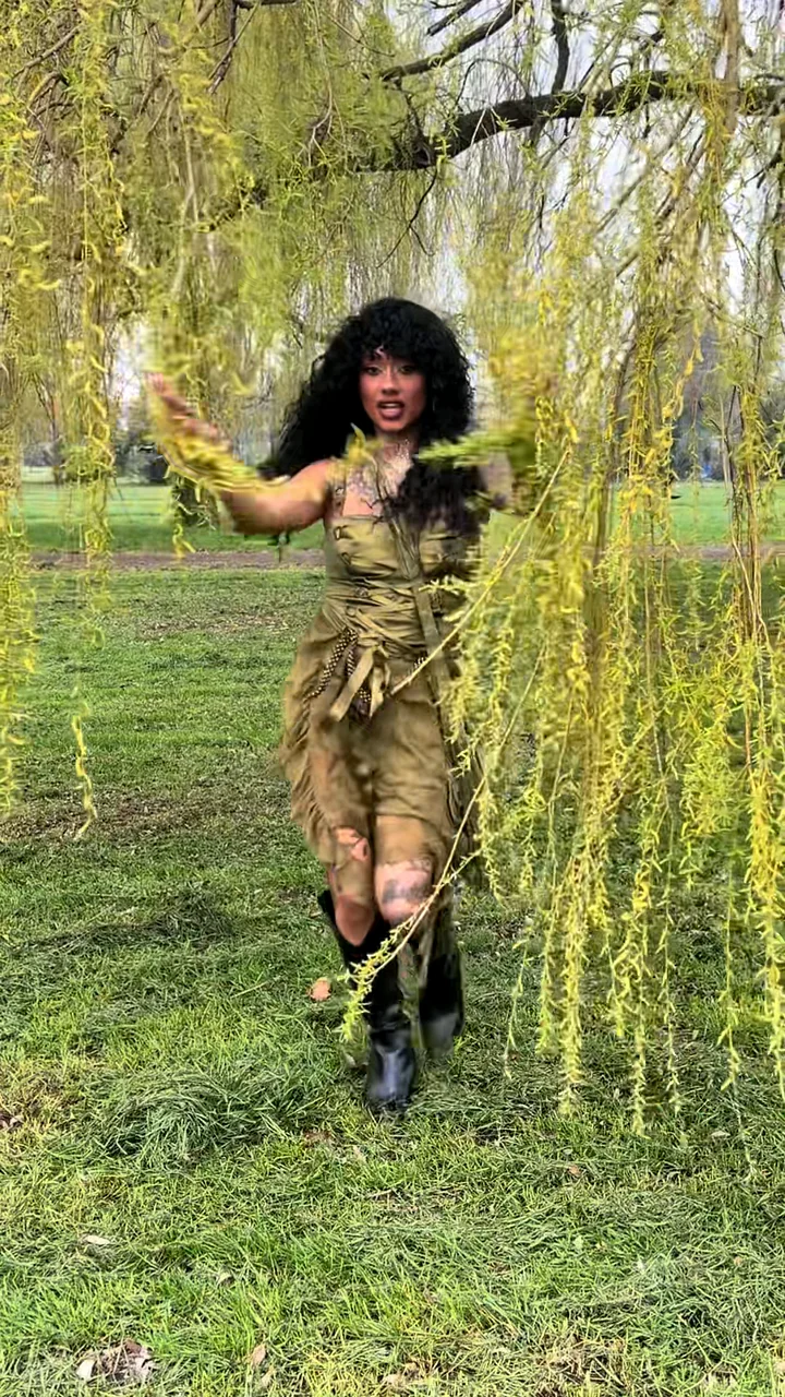 Creator dancing out of willow trees at a garden festival