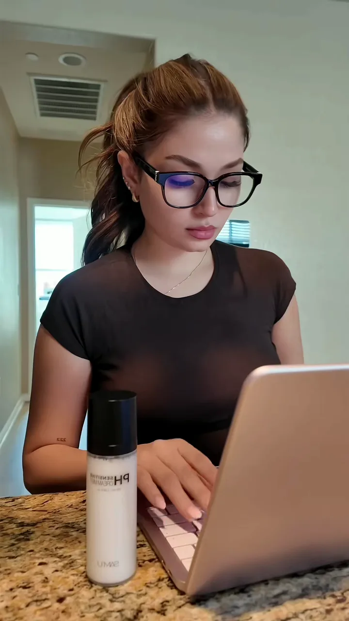 Creator in glasses typing on a laptop at a kitchen counter