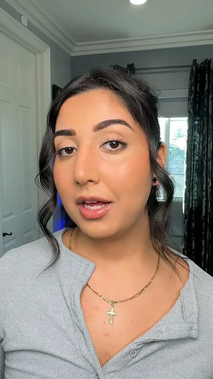 Creator with dark wavy hair talking to camera in a bedroom