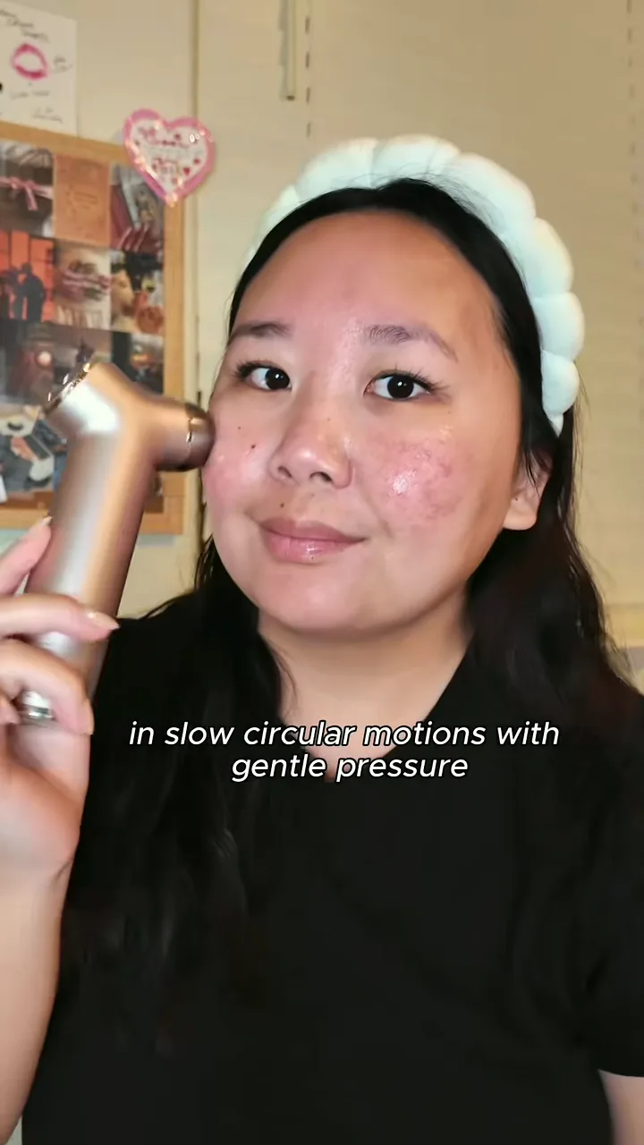 Creator in a fluffy headband moving a gold handheld facial device in circles on her cheek