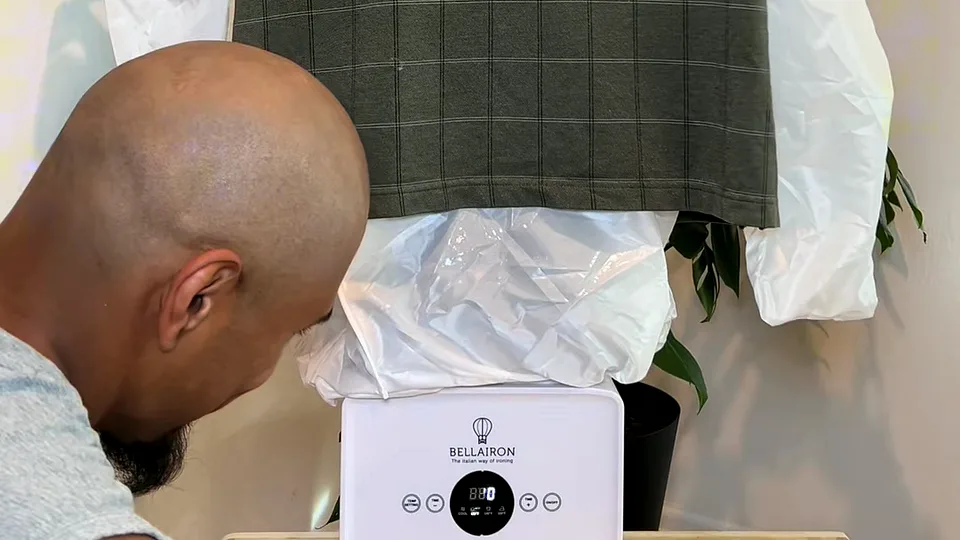 Bald man leaning in to watch a Bellairon unit inflate a checked shirt draped over its white base