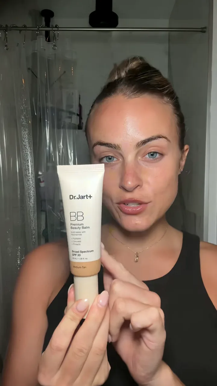 Creator holding a cream tube to camera and pointing at it