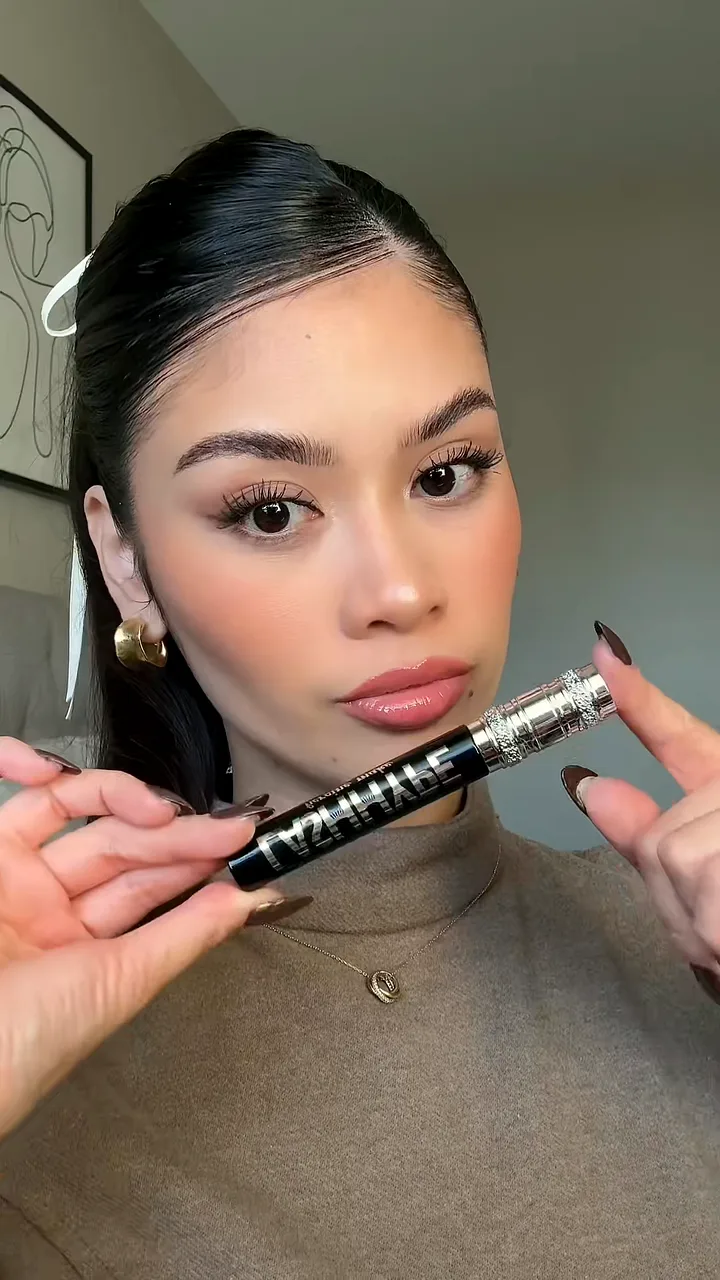 Creator holding a mascara tube under her eye