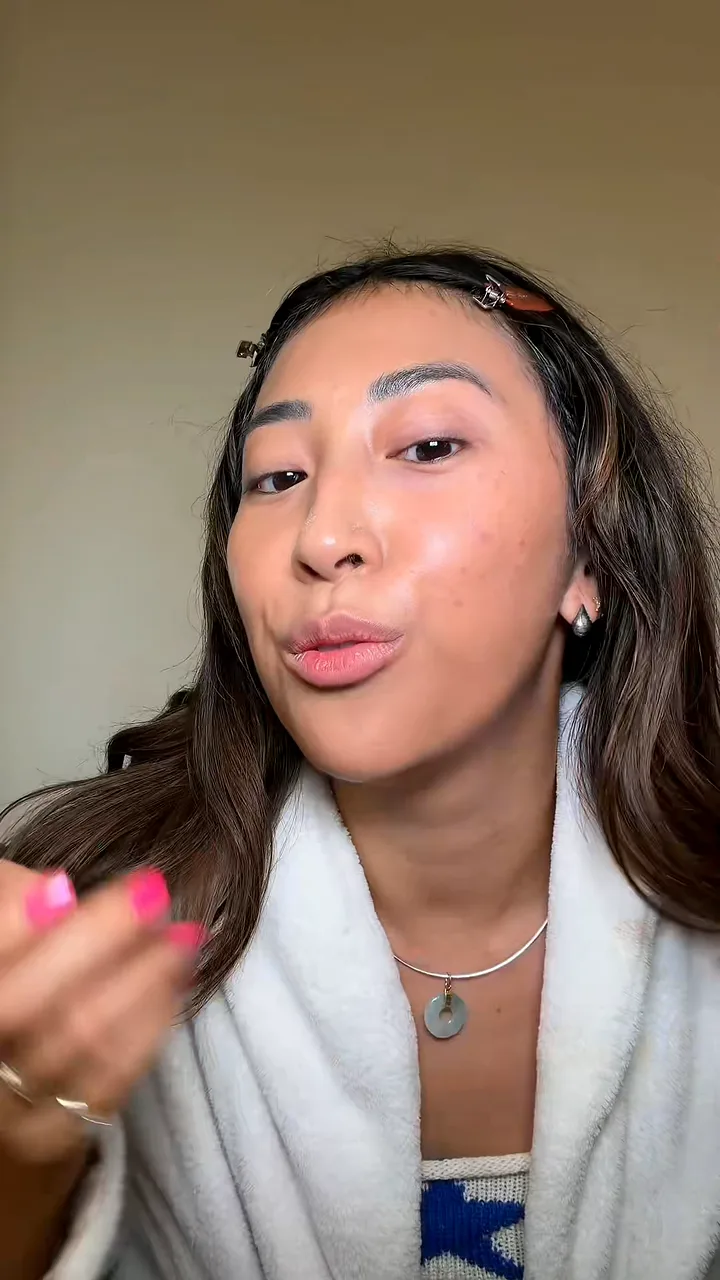 Creator in a white robe talking to camera while her hair is styled